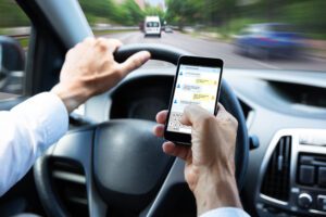 Man texting on his cell phone while driving a cae