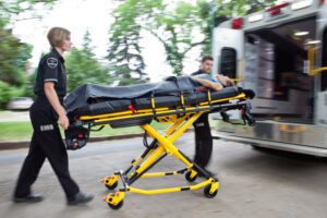 Image of paramedics loading an elderly woman into the ambulance on a stretcher