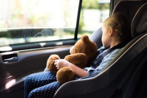 Image of little girl asleep in a carseat holding a teddy bear