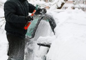 Image of a person scraping ice and snow from their car