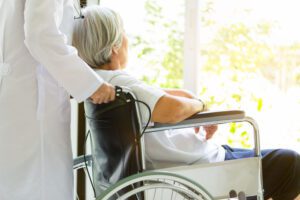 Image of medical professional pushing elderly woman in wheelchair