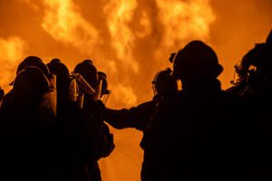 Image of firefighters standing in front of a large fire