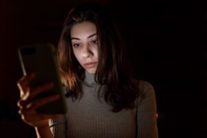 Image of woman looking at her cell phone in the dark