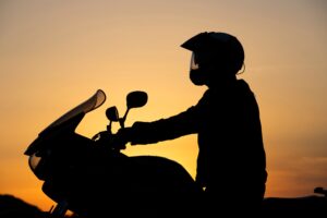 Silhouette of person on motorcycle at sunset