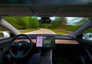 Image of person driving a Tesla on autopilot