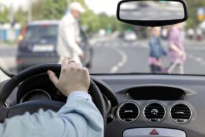 Image of person driving a car with pedestrians in the crosswalk