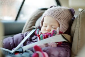 Image of sleeping toddler in winter coat in car seat