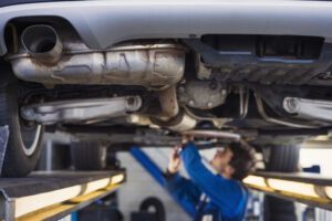 Image of man working on a car that is raised on a lift