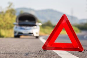 Image of vehicle broken down on the side of the road with a red emergency triangle