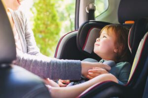 Image of happy toddler being buckled into her carseat