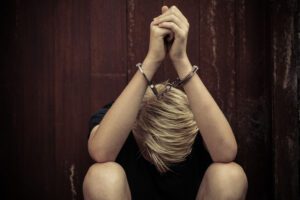 Image of young teenager in handcuffs with his head down