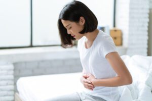 Image of woman holding her stomach to indicate abdominal pain