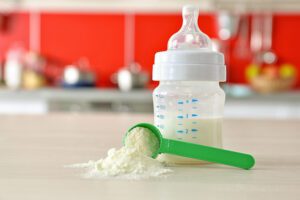 Image of a baby bottle on a counter with a scoop of baby formula