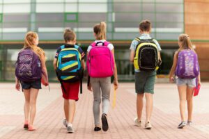 Image of 5 school children walking away from the camera with backpacks on