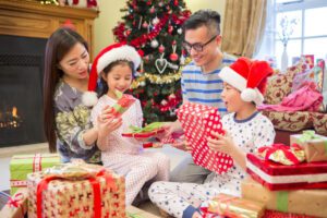 Image of happy family openings gifts by christmas tree and fireplace