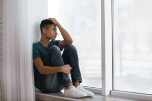 Image of person looking sad, sitting by a window