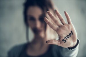 Image of woman holding her hand up with the word stop! written on her palm