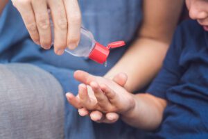 Image of person pouring hand sanitizer in small child's hand