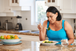 Image of woman looking unhappy while eating a plate of food