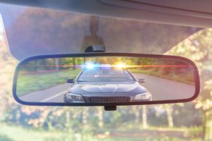 Image of police car with lights on in rearview mirror