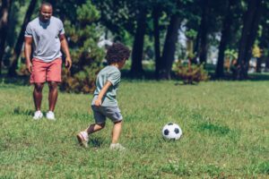 Image of man playing soccer with a young boy