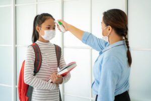 Image of student wearing a mask having her temperature taken