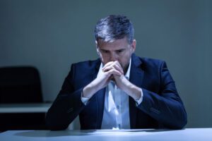 Image of sad man with his hands folded in front of his face