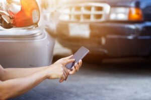 Image depicting a man using his cell phone at a car accident