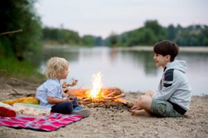 Image of two kids having a picnic near a campfire