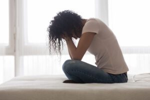 Image of woman sitting on a bed with her face in her hands