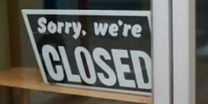 Image of a sorry we're closed sign in a store window