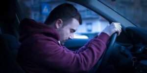 Image of man looking sad or tired driving a car