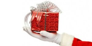 Image of Santa Claus hand holding a red gift with a silver bow