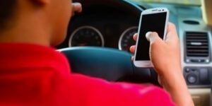 Image of person using their cell phone while behind the wheel of a vehicle