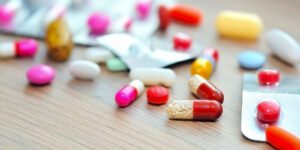 Image of various colorful pills in blister packs and loose on the table