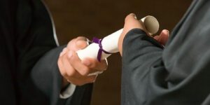 Image of a person handing a diploma to a graduate