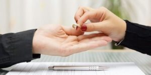 Image of a woman handing her wedding ring to a man