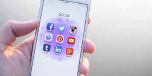 Image of hand holding phone with social media icons displayed