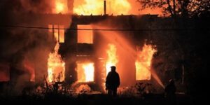 Image of man standing in front of a large structure fire