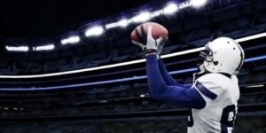 Image of Dallas Cowboy football player catching a football on the field with stadium lights in the background