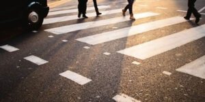 Image of pedestrian feet walking across a crosswalk with a car waiting