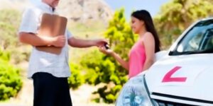 Image of a person handing kets to a teen driver next to a car