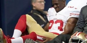 Image of an injured Reggie Bush in a red, white, and gold football uniform holding his leg in pain