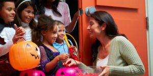 Image of woman giving trick or treaters candy at the door