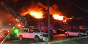 Image of a large apartment fire with vehicles and fire truck