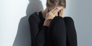 Image of woman covering her face sitting on the floor