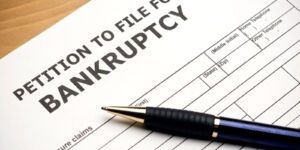 Image of petition to file for bankruptcy document with a blue pen