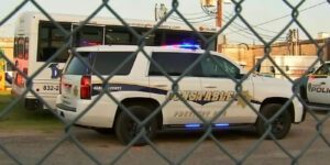 Image of police vehicles behind a chain link fence