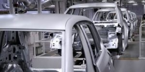 Image inside a vehicle manufacturing plant with metal car frames on an assembly line