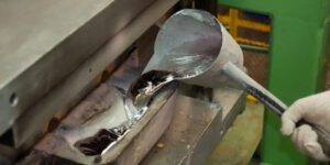 Image of worker pouring melted metal into a machine